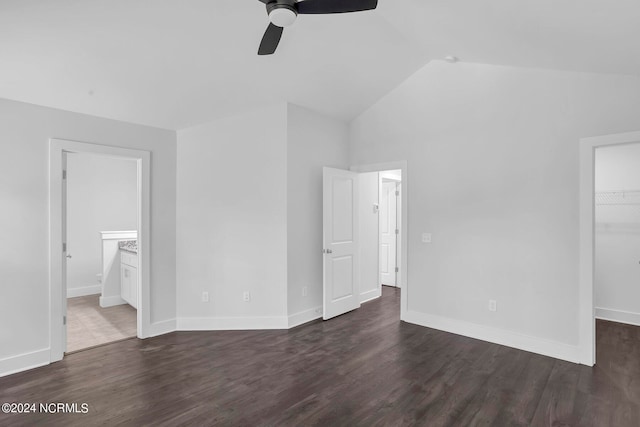 unfurnished bedroom with vaulted ceiling, a walk in closet, dark hardwood / wood-style flooring, a closet, and ceiling fan