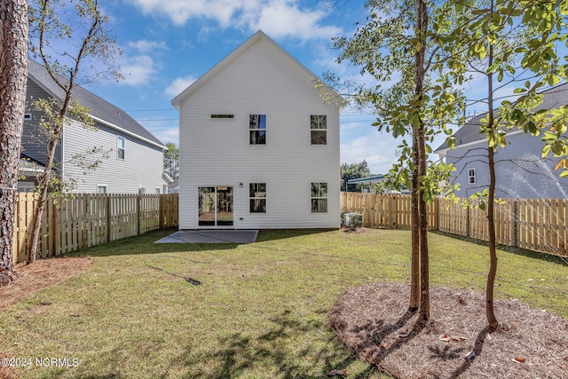 rear view of house featuring a lawn and a patio