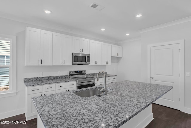 kitchen featuring dark stone countertops, appliances with stainless steel finishes, dark hardwood / wood-style flooring, and a kitchen island with sink