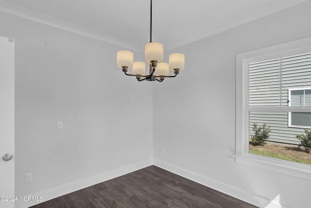 unfurnished dining area featuring ornamental molding, dark wood-type flooring, and a chandelier