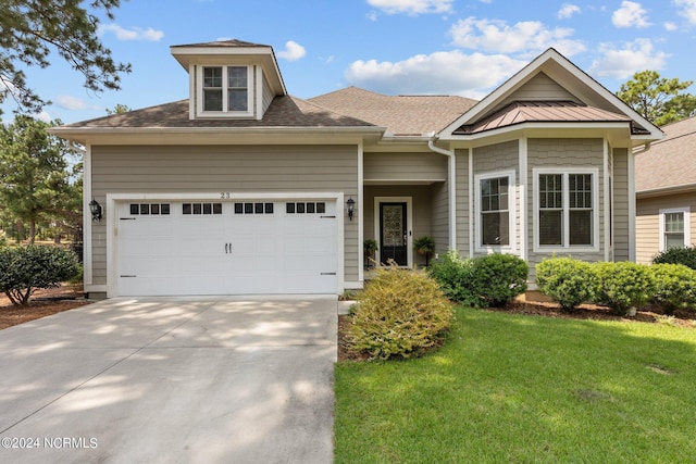 view of front of house featuring roof with shingles, an attached garage, a front yard, metal roof, and driveway