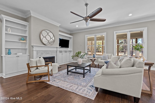 living room with ornamental molding, a brick fireplace, dark wood finished floors, and a ceiling fan