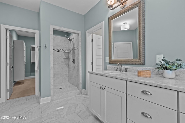 full bathroom featuring marble finish floor, baseboards, tiled shower, and vanity