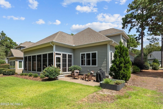 rear view of property with a sunroom, roof with shingles, a lawn, and a patio