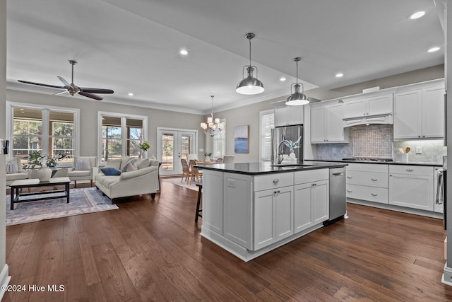 kitchen with a sink, white cabinets, open floor plan, dark countertops, and dark wood finished floors