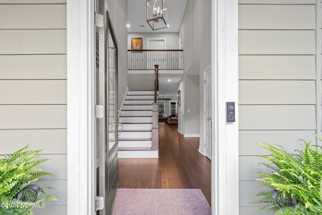 interior space with a towering ceiling, dark wood-style floors, stairs, and baseboards