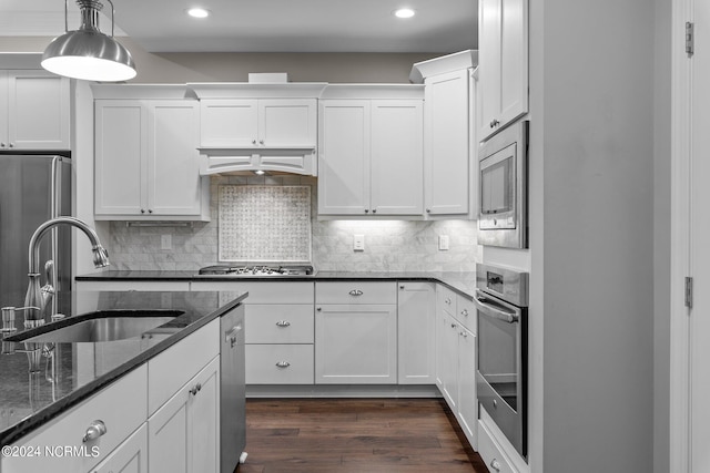 kitchen featuring stainless steel appliances, tasteful backsplash, dark wood-type flooring, white cabinetry, and a sink