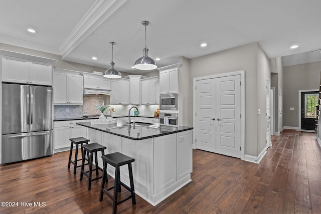 kitchen with dark wood finished floors, dark countertops, decorative backsplash, appliances with stainless steel finishes, and a sink