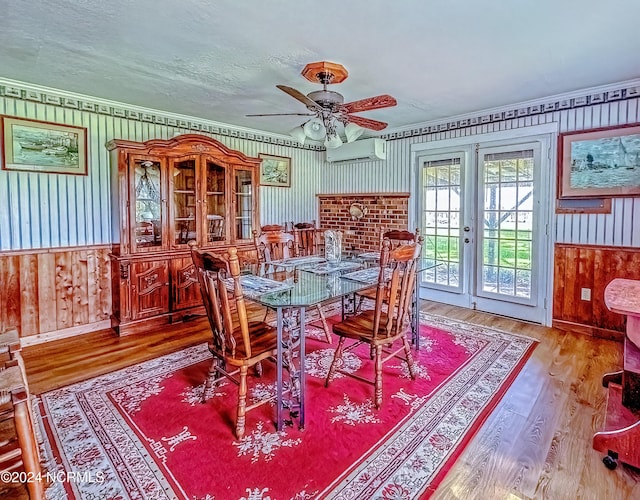 dining room featuring a wainscoted wall, french doors, a wall unit AC, and wood finished floors