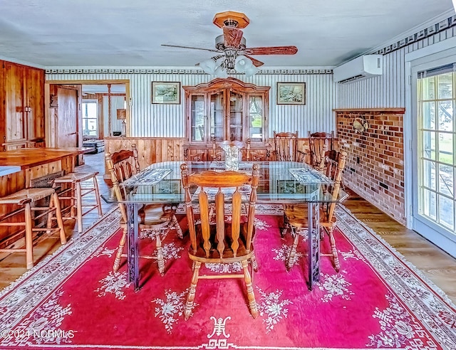 dining area featuring a wall mounted AC, wood finished floors, and crown molding