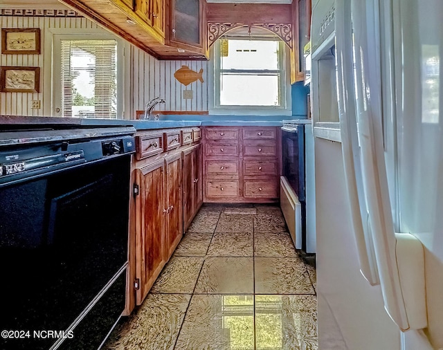 kitchen featuring a sink, glass insert cabinets, dishwasher, and freestanding refrigerator