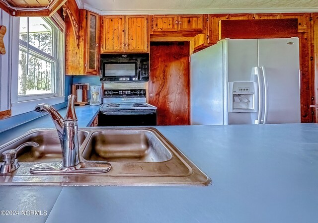 kitchen featuring black microwave, white fridge with ice dispenser, brown cabinetry, and electric stove