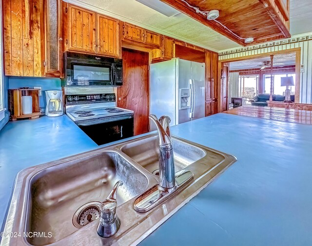 kitchen featuring brown cabinets, electric range oven, a sink, refrigerator with ice dispenser, and black microwave