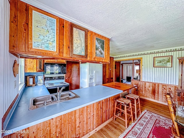 kitchen featuring electric stove, fridge with ice dispenser, a sink, wood finished floors, and black microwave