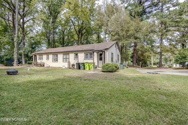 view of front of property with cooling unit, a front yard, and a fire pit