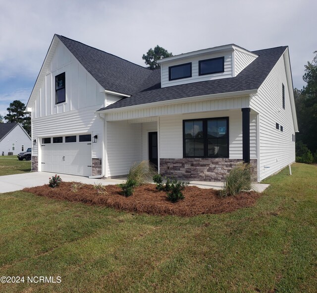 view of front of home with a front lawn, covered porch, and a garage