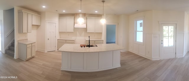 kitchen featuring a kitchen island with sink, light wood-type flooring, pendant lighting, a sink, and recessed lighting