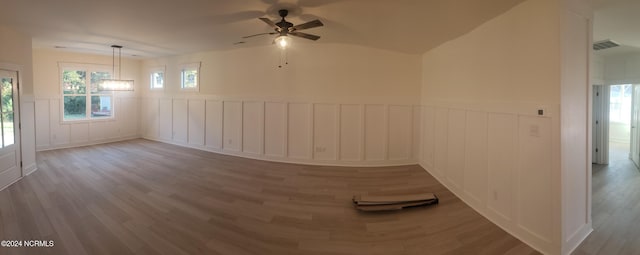 unfurnished room featuring wainscoting, wood finished floors, and a healthy amount of sunlight