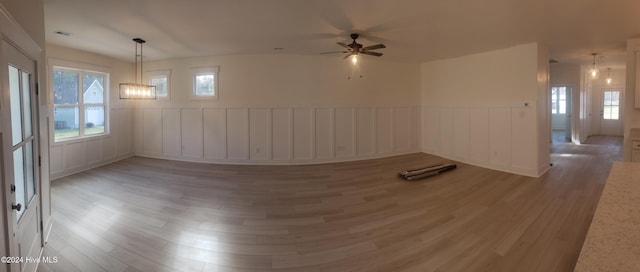 spare room with a wainscoted wall, a decorative wall, and wood finished floors