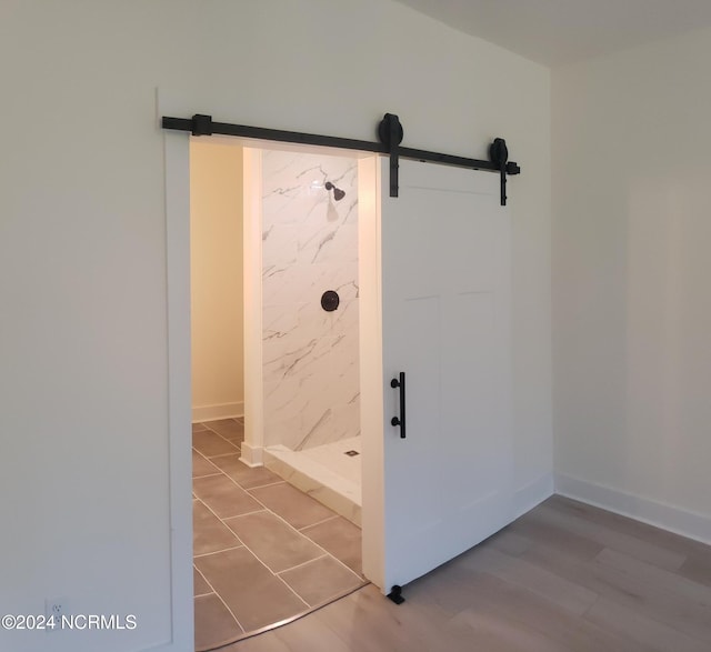 bathroom with a stall shower, wood finished floors, and baseboards