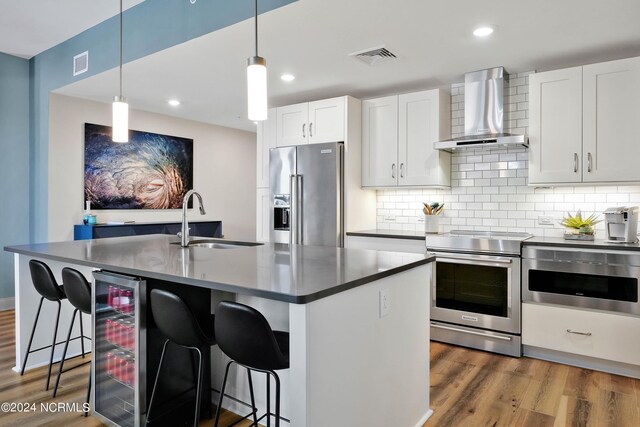 kitchen with wine cooler, appliances with stainless steel finishes, dark wood-style floors, wall chimney exhaust hood, and a sink