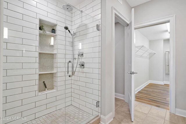 bathroom with tile patterned floors, a shower stall, and baseboards