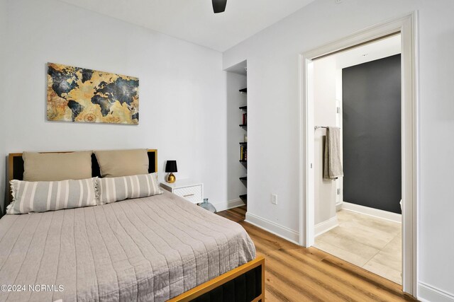 bedroom featuring light wood-style flooring, ensuite bathroom, and baseboards