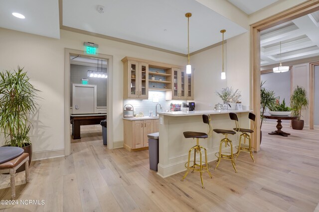 kitchen with light wood finished floors, a breakfast bar, a sink, light countertops, and glass insert cabinets