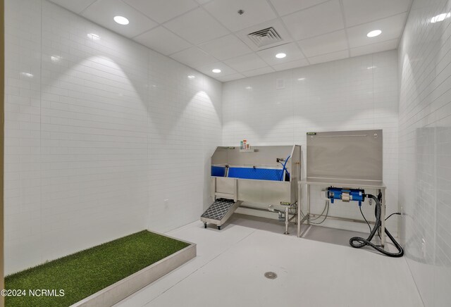 misc room featuring tile walls, a paneled ceiling, visible vents, and concrete floors