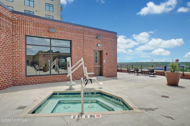 view of swimming pool with fence, a community hot tub, and a patio area