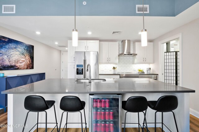 kitchen featuring visible vents, stainless steel appliances, wall chimney exhaust hood, and a sink