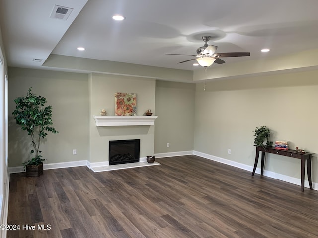 unfurnished living room featuring dark hardwood / wood-style flooring, a tray ceiling, and ceiling fan