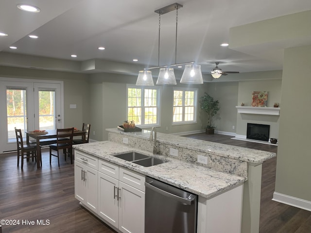 kitchen featuring pendant lighting, white cabinetry, dishwasher, sink, and a kitchen island with sink