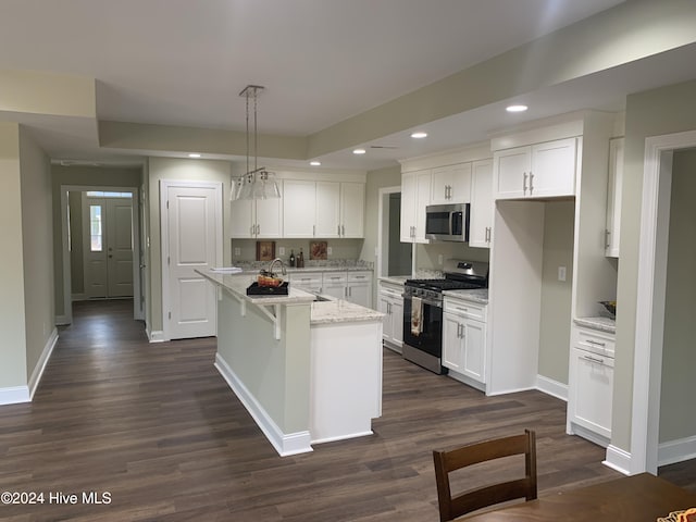 kitchen featuring pendant lighting, a kitchen island with sink, stainless steel appliances, light stone counters, and white cabinets