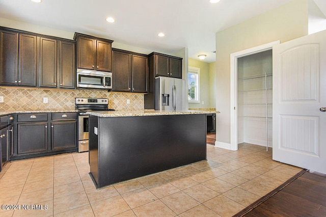 kitchen featuring appliances with stainless steel finishes, light stone counters, and a kitchen island