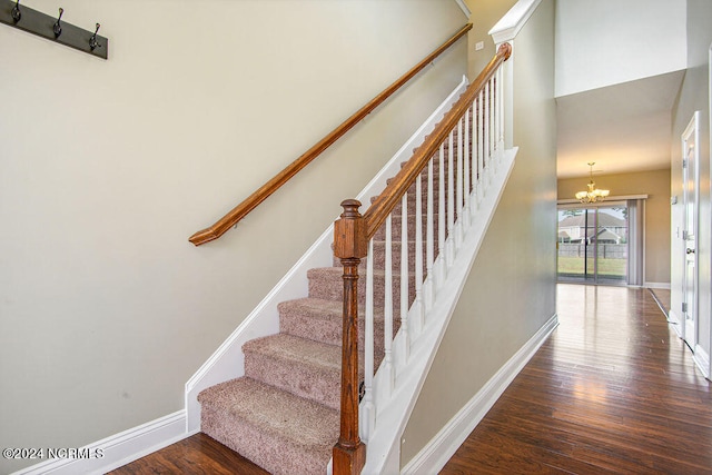 stairway featuring wood-type flooring and an inviting chandelier