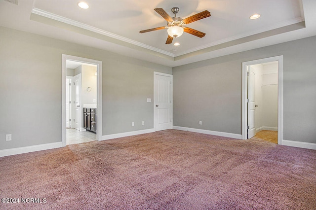 unfurnished bedroom featuring ornamental molding, a spacious closet, ceiling fan, and a raised ceiling