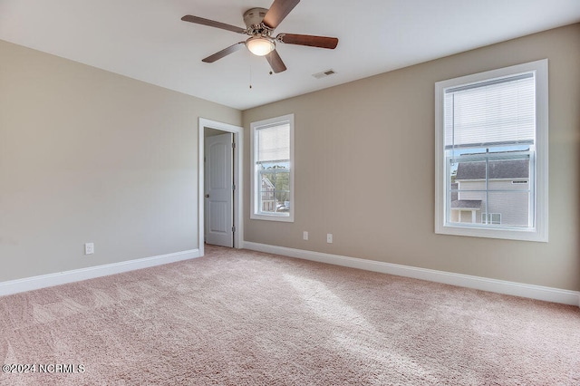 spare room featuring a healthy amount of sunlight, carpet, and ceiling fan