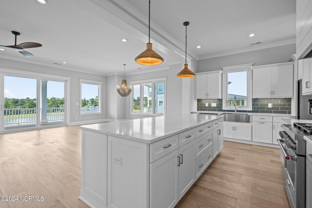 kitchen with stainless steel range, light hardwood / wood-style flooring, a center island, ceiling fan, and white cabinets