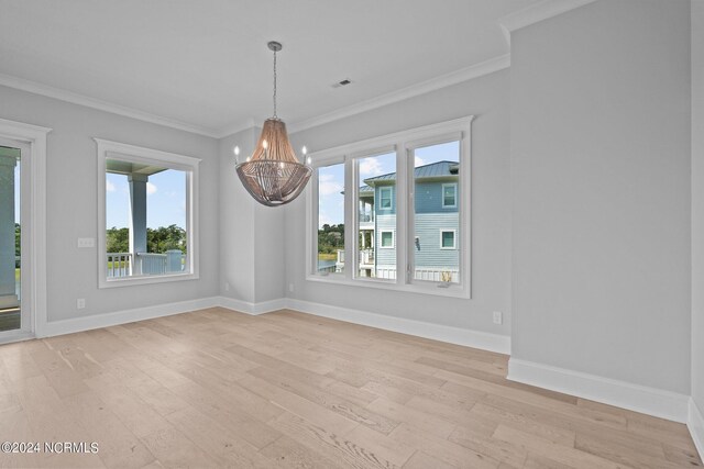 empty room featuring a wealth of natural light, light hardwood / wood-style flooring, and a chandelier