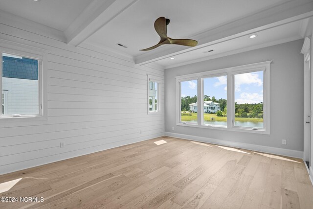 unfurnished room with beamed ceiling, light hardwood / wood-style floors, crown molding, ceiling fan, and wooden walls