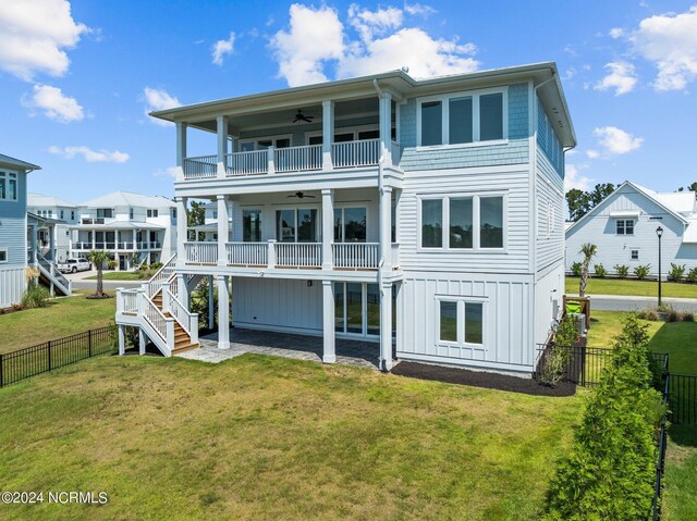 rear view of house with a yard, ceiling fan, and a balcony