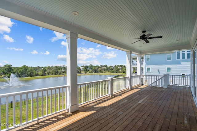 deck with a water view, a lawn, and ceiling fan