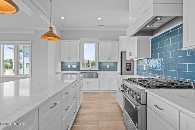 kitchen with light hardwood / wood-style flooring, stainless steel stove, hanging light fixtures, custom range hood, and white cabinets