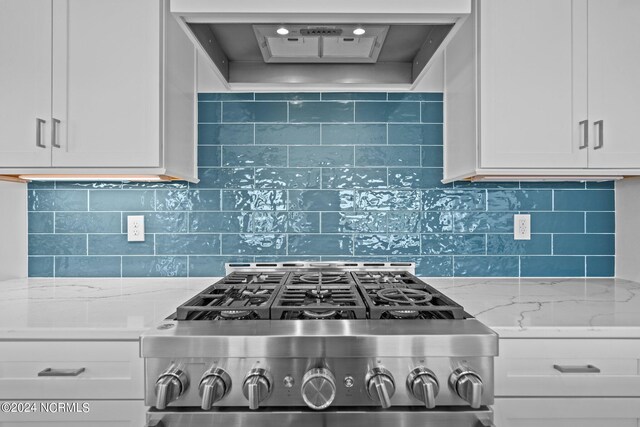 kitchen featuring custom exhaust hood, stainless steel stove, light stone countertops, and white cabinets