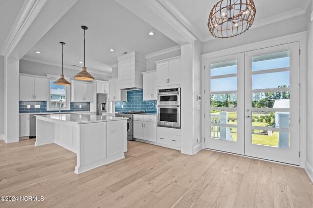 kitchen featuring decorative light fixtures, appliances with stainless steel finishes, a kitchen island, and light hardwood / wood-style floors