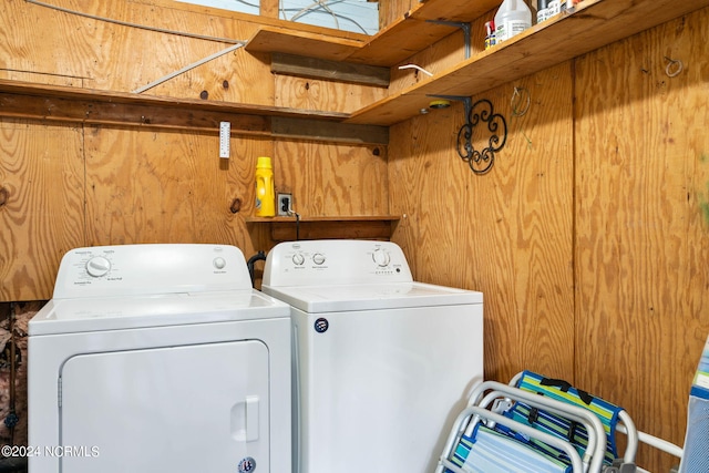 laundry room with wooden walls and washing machine and dryer