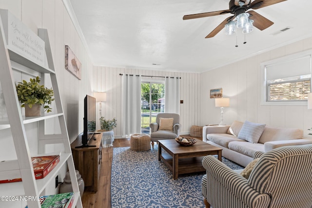 living room featuring ceiling fan, wood walls, hardwood / wood-style floors, and ornamental molding