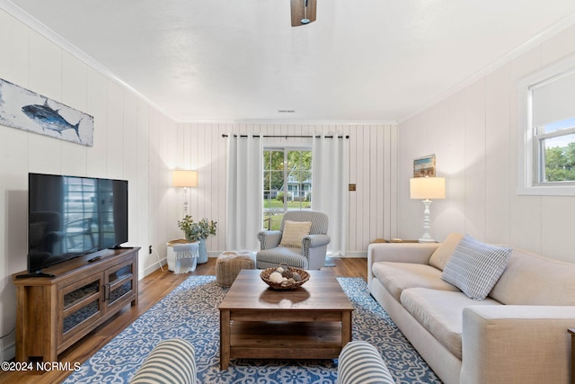 living room with wood-type flooring, ornamental molding, and a healthy amount of sunlight