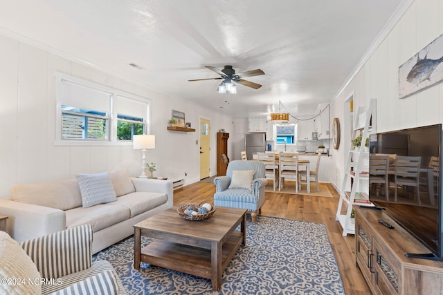 living room featuring crown molding, light hardwood / wood-style floors, ceiling fan, and a baseboard radiator